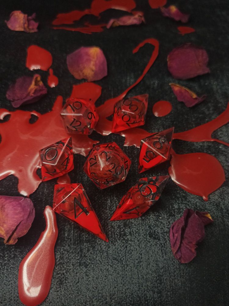 gory blood red dice with black lettering on black velvet and bloodsplatter background 