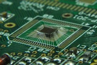 A photo of a die bonded to a circuit board using many many separate little bonding wires