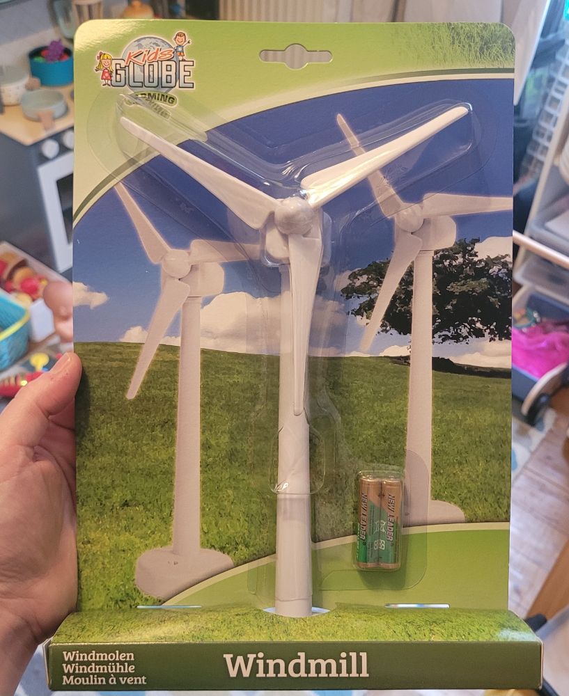 A hand holding a white turbine toy with batteries included in the packet.