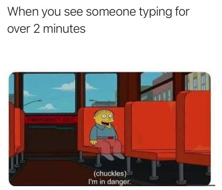 A meme of Ralph Wiggum, a small child character in The Simpsons, sits on a school bus with red seats. Ralph Wiggum has yellow skin, red trousers, a blue shirt and a big grin on his face. The quote is in white text at the bottom of the image, and says "(chuckles) I'm in danger". The image of the cartoon is under a block of black text on a white background, which says "when you see someone typing for over 2 minutes"