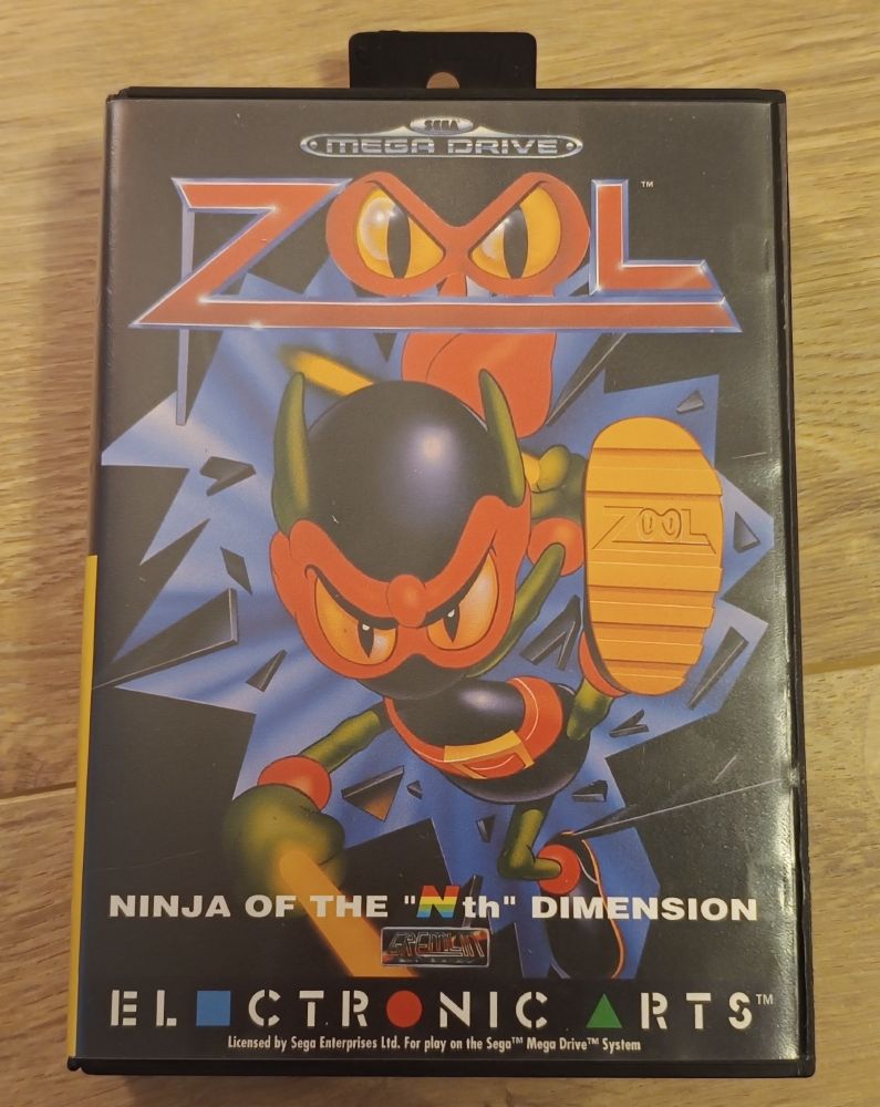 The front cover of Zool for the Sega Mega Drive. Zool is breaking through the box with a kick, and the sole of his shoe bears his name.