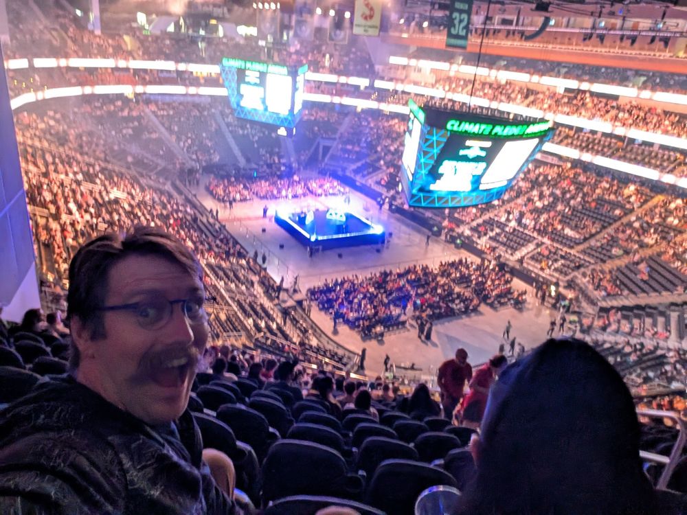 Robert in front of stadium seating at Climate Pledge Arena in Seattle for Dimension 20!