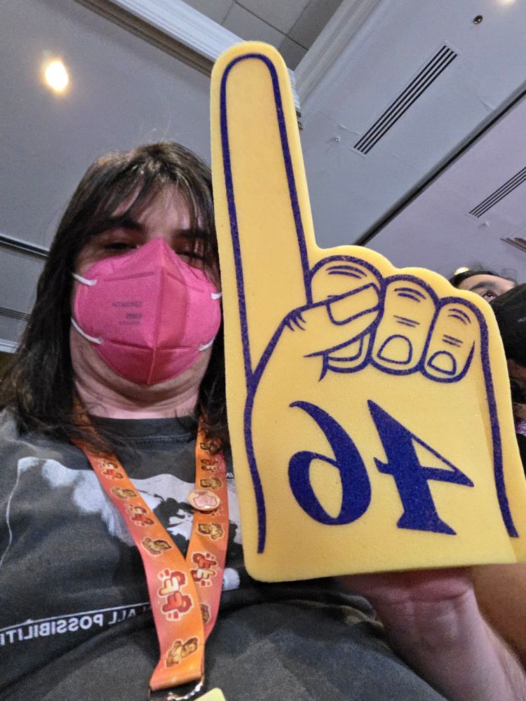 A selfie of Burtch holding up a yellow foam finger with the number 46 on it.