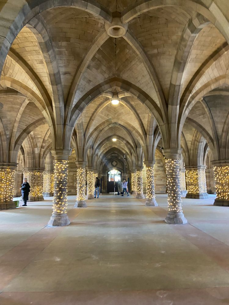 Stone arches with string lights lit up on the stone columns 