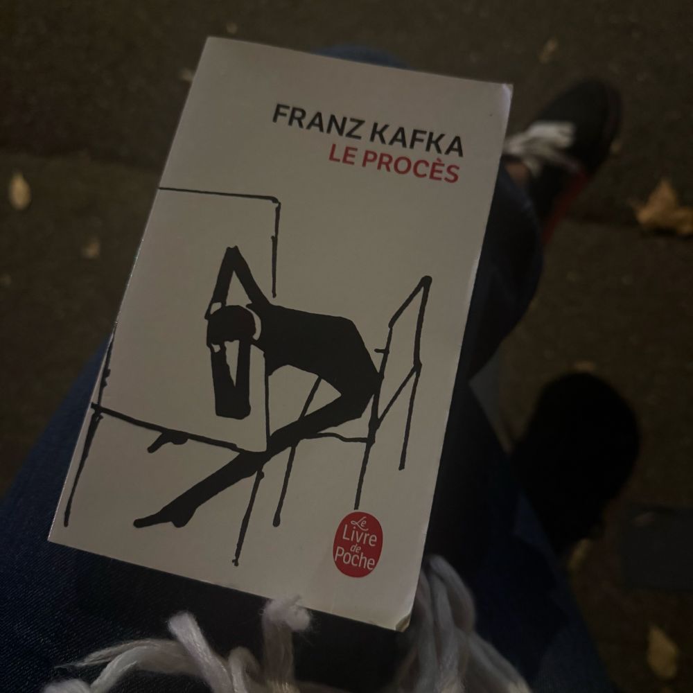 Photo de la couverture d’un livre, fond blanc, illustration silhouette d’un homme assis devant une table la tête entre ses bras.
Auteur : Franz Kafka
Titre : LE PROCÈS 
Édition : Le Livre de Poche