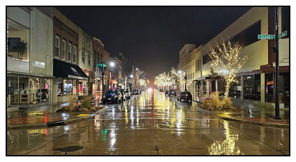 Downtown street with Christmas lights reflected in nighttime rain in Eau Claire, Wisconsin.