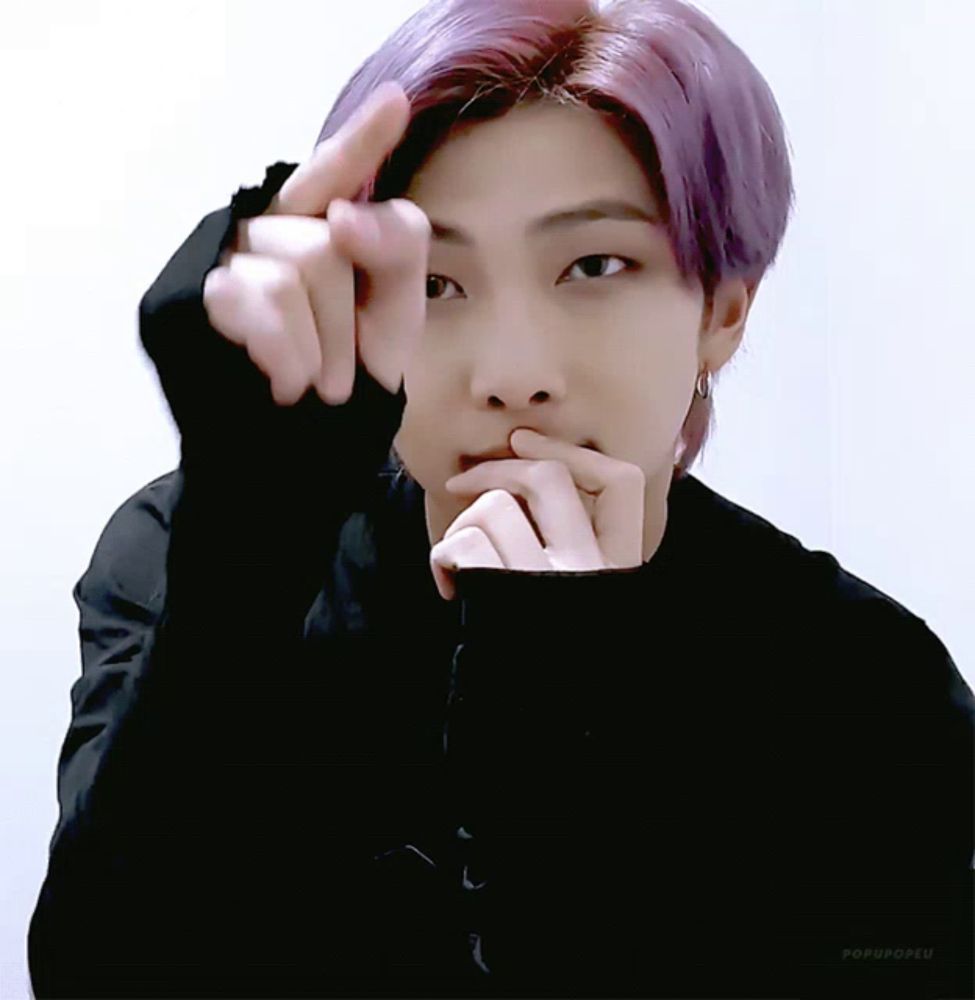 a person with purple hair is making a heart shape with their finger