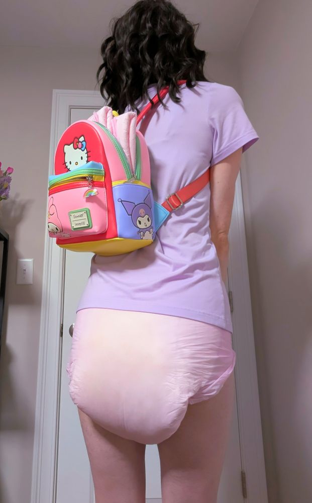 Backside of a person, their pink diaper on full display. A hello kitty backpack slings over their shoulder, with extra diapers sticking out