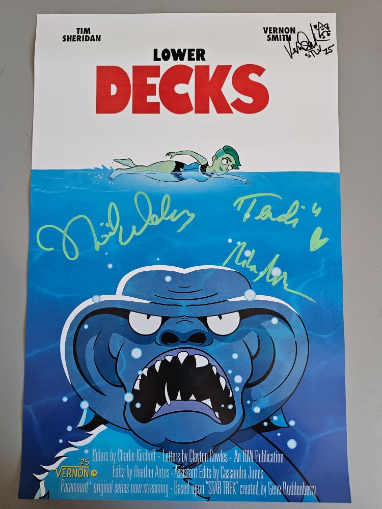 11x17 print of a comic book from Lower Decks depicting the poster from Jaws. With a Ferengi coming up from the deep water to a swimming Tendi. The comic book print was signed by Noel Wells, Vernon Smith (the artist) and Lower Decks creator Mike McMahan at STLV.