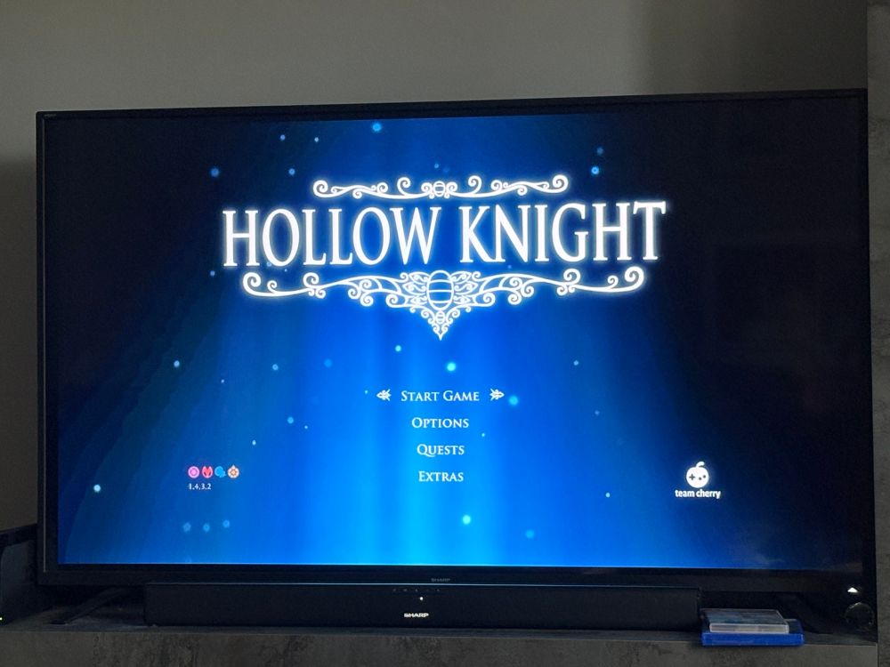 A television showing the title screen for the video game Hollow Knight