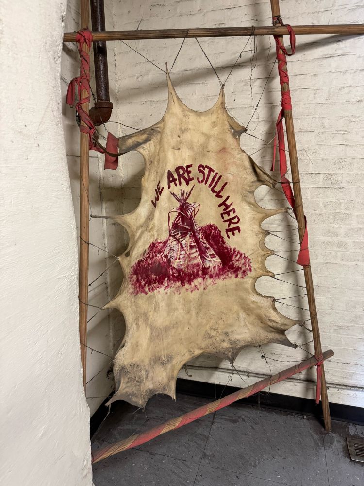 Tanned hide on frame with "WE ARE STILL HERE" and painting of teeepee