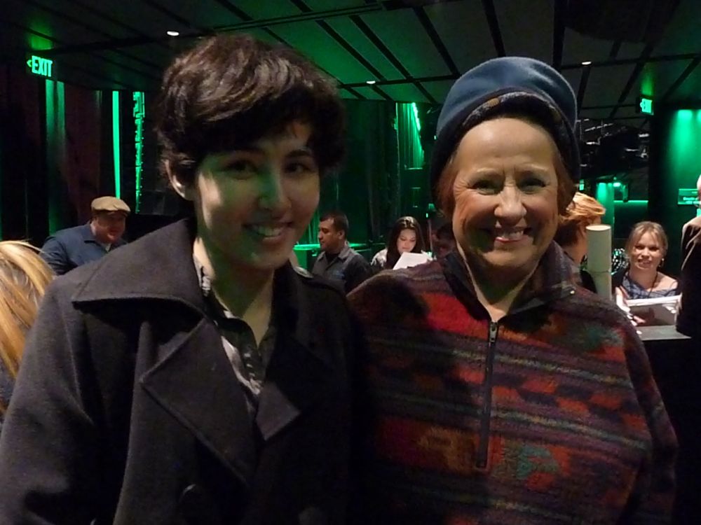 photo from 2010. a student in a black peacoat poses next to Lynne Marie Stewart, who is wearing a fleece hat and vibrant popover fleece.