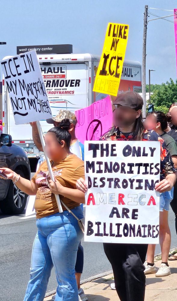Protestors in Kalamazoo, MI holding signs that read, "ICE in my Margaritas, not my streets", "The only minorities destroying America are billionaires", and "I like my ICE crushed"