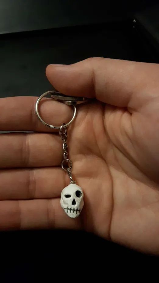 skull key charm with sly expression, sculpted in Cosclay polymer clay. Now painted: white with black eye holes, nose hole, and teeth lines.