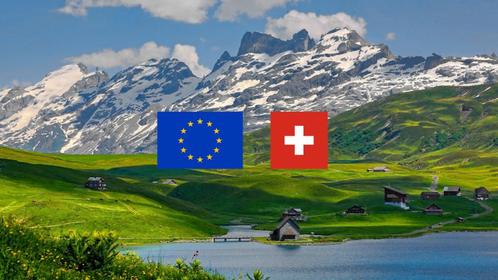 Image d’illustration représentant des montagnes suisses, avec au premier plan un drapeau de l’Union européenne et un drapeau suisse, côte à côte. 