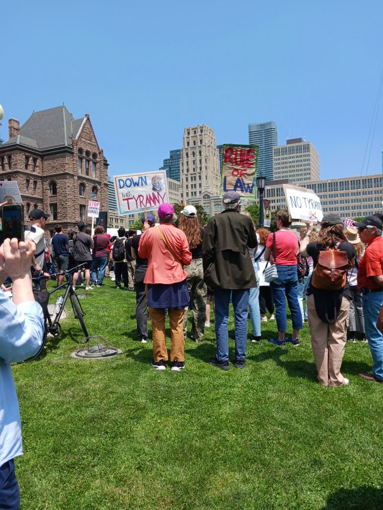 Signs and group of people from the Toronto Ontario Canada No Kings/Tyrants March. Signs read "Down with Tyranny" and "No Tyrants."