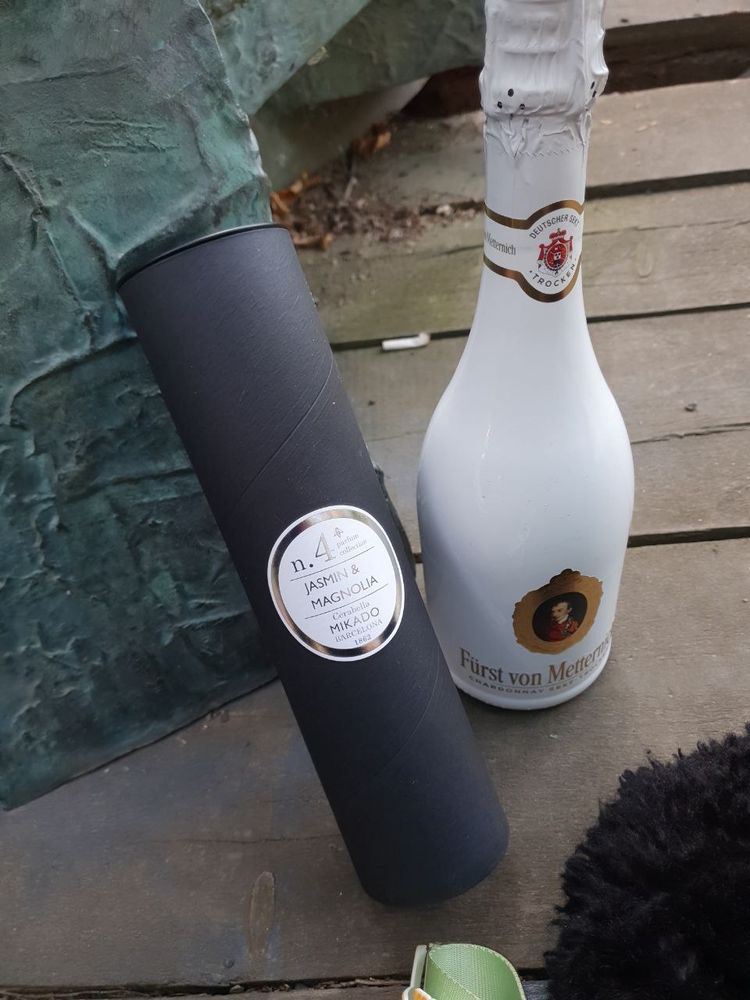 A bottle of champagne and a cylindrical box with perfume
