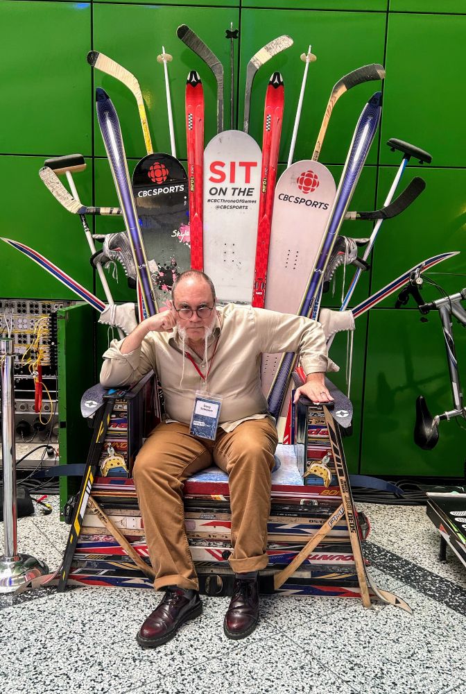 Doug sits on a throne made of sports equipment. it is reminiscent of the GOT throne of swords