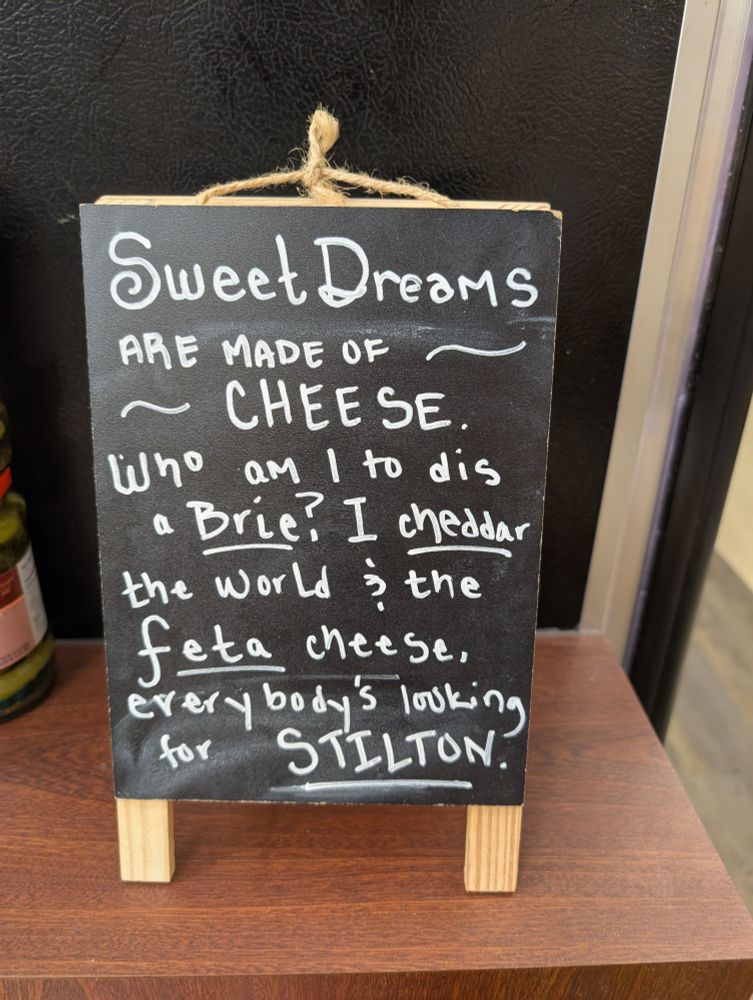 Chalkboard sign with lyric parody: sweet dreams are made of cheese
Who am I to dis a brie. I cheddar the world and the feta cheese. Everybody's looking for Stilton 

