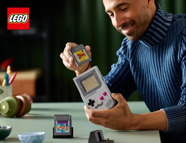 Promtional image for the Lego Game Boy showing some guy inserting the The Legend of Zelda cartridge the wrong way around.