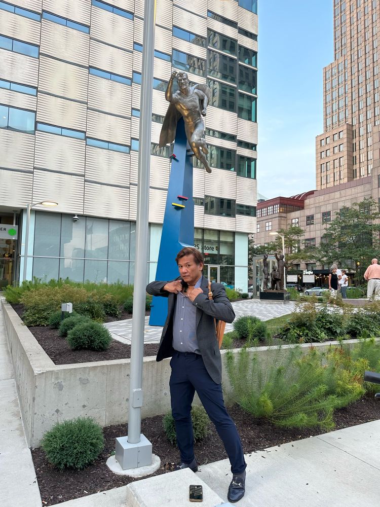 Hey, isn’t that @dallasnews.com editor @bobbycalvan.bsky.social paying homage to Clark Kent at the new #Superman statue at the #Cleveland Convention Center? Bruh, the phone booth is right behind you! 😂 #BirthplaceOfSuperman (Journalist Bobby Caina Calvin pretends to change into his Superman outfit at the base of the flying Superman statue in Cleveland) @thisiscle.bsky.social 