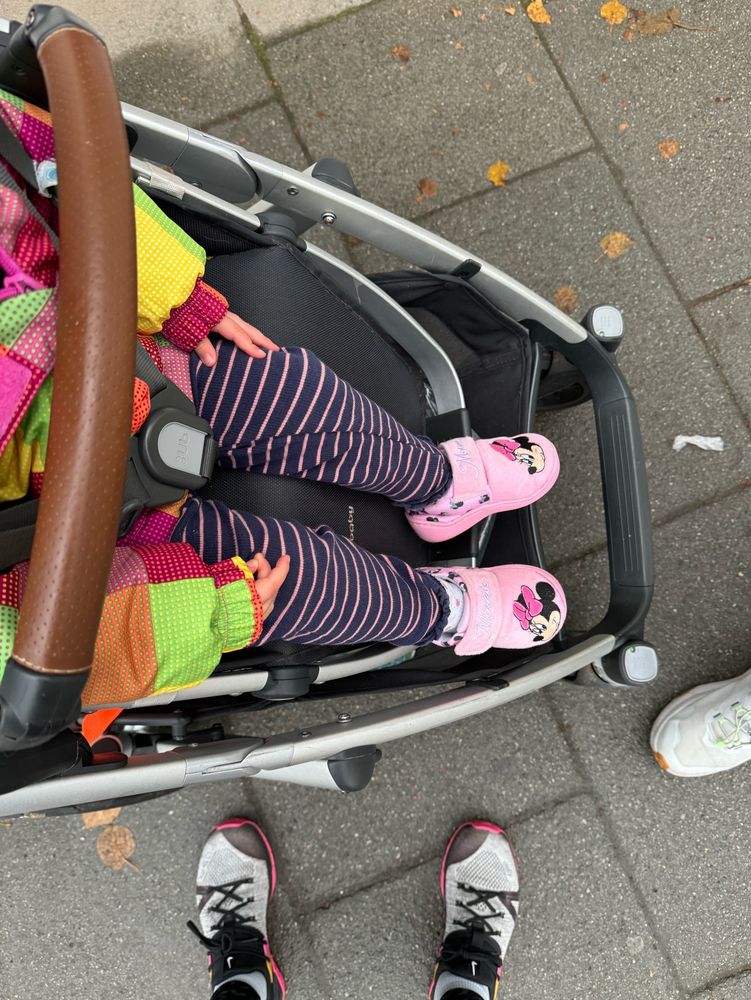 Birds Eye view of buggy with toddler’s feet wearing pink Minnie Mouse slippers 