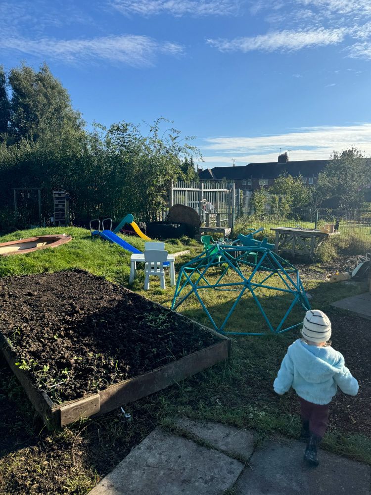 Toddler at a community garden with a climbing frame