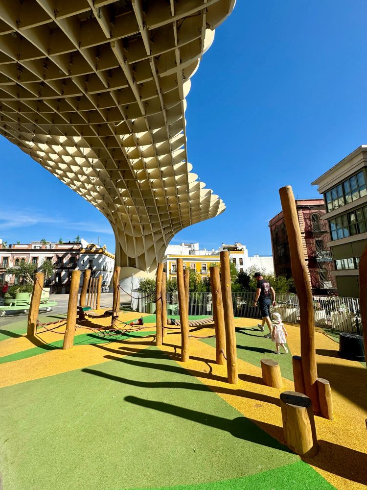 Man and toddler walking underneath a waffle shaped structure in the sunshine