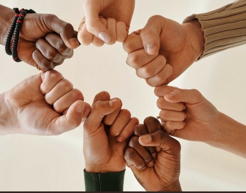 Image shows fists, hands amd srms together in a display of unity and solidarity.