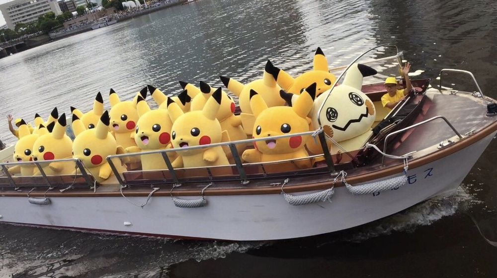 picture of the mimikyu mascot having joined the group of pikachu mascots on a boat in the water 
