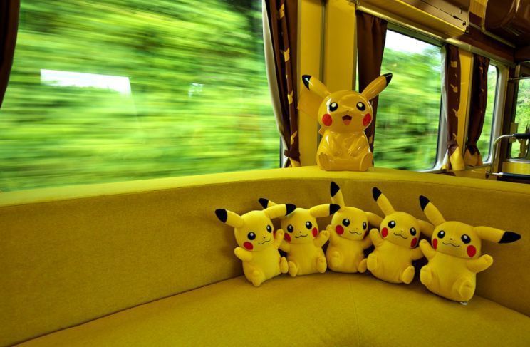 Picture of the inside of a pikachu themed train showing pikachu plushes sitting in the seats 