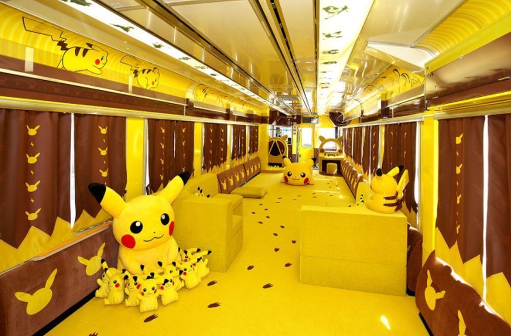 Picture of the inside of a pikachu train showing pikachu plushes and pikachu theming on the walls and floor of the train 