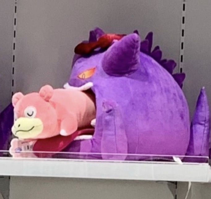 A plush of gigantamax Gengar appearing to be eating a sleeping slowpoke plush 
