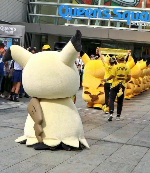 picture of a mimikyu mascot behind a group of pikachu mascots staring at them 
