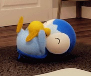 screenshot of a Pokémon animation showing a piplup playing with a yellow ball on a rug 