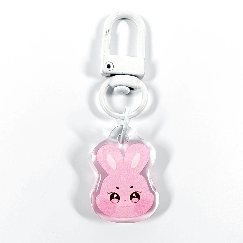 A picture of an acrylic keychain of Seonghwa's Aniteez animal from the K-Pop group ATEEZ. It's the head of the pink rabbit smiling like his original design. The rim of the keychain is clear. It has a white clasp.