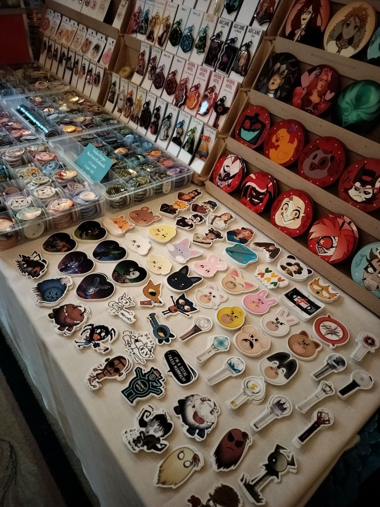 A close up of the middle of the table where you can see stickers, coasters, badges and keychains.