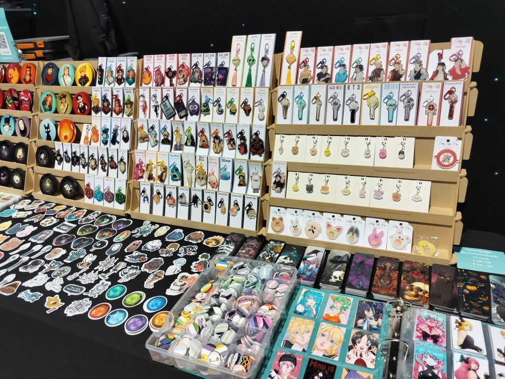 A close-up of the right side of the table where you can see keychains, coasters, stickers, bookmarks and mini prints more closely.