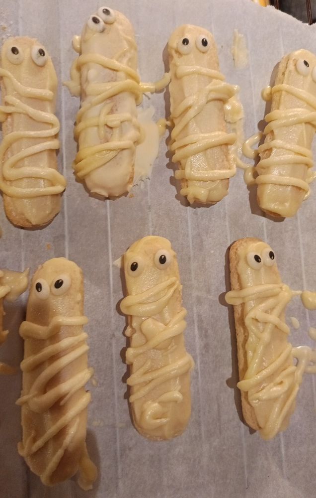 Löffelbiskuits mit weisser Schokolade überzogen.
2 Zuckergussaugen
Weissen Schokostreifen drübergepfrimelt
Sollten Mumien sein