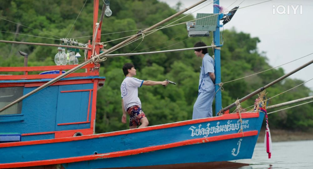 screenshot from the the heart killers where first and khaotung's characters are having an emotional time on a boat thinking about love and death, but with very different vibes bc a gun is also present.