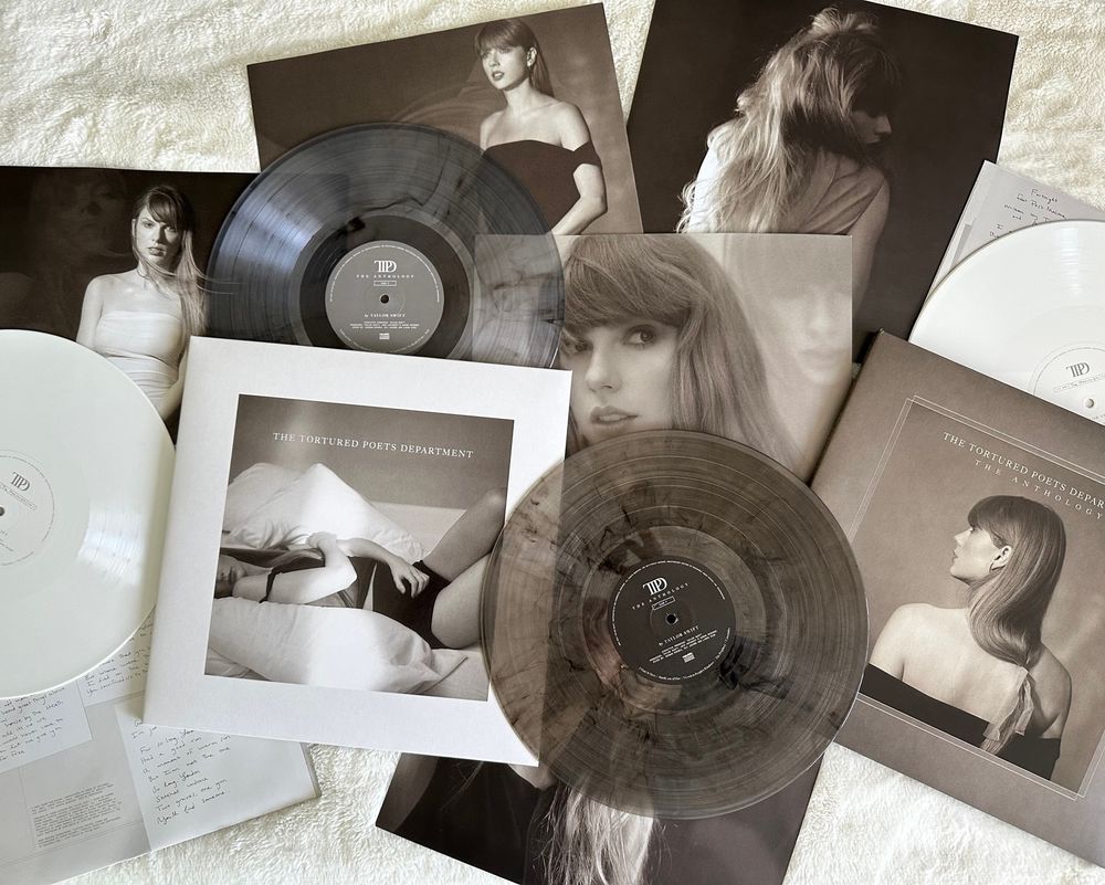 A picture I took of my the tortured poets department vinyls and all the sleeves/lyrics/posters that come with it scattered on a white blanket