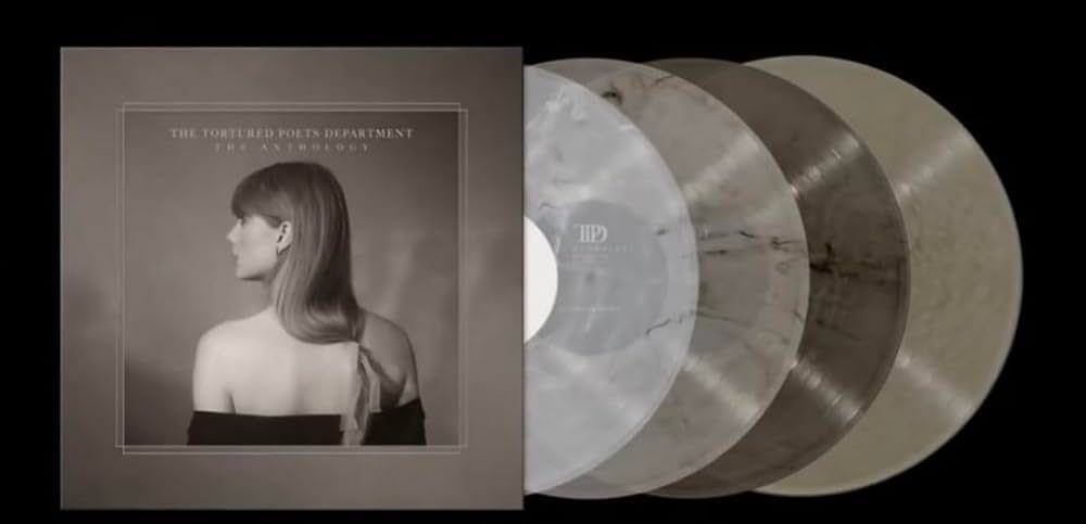 The Tortured Poets Department The Anthology vinyl. This vinyl consists of four discs each with a different translucent marbled color. There is a light grey, a dark grey, a gold metallic and a beige vinyl. The album cover is different from the streaming album cover for this album. It shows taylor swift from the back side and she is looking at the left, her hair is straight and there is something tied in the ends of her hair, she is wearing a black off shoulder top. The picture is in a box with a thick border around it and it says the album cover on it. The cover is mainly beige colors