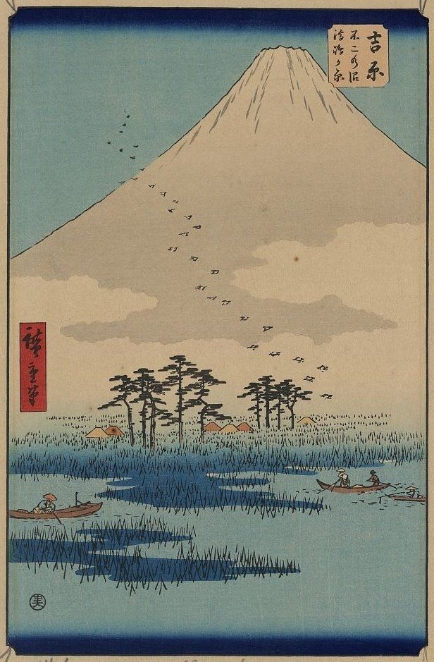 Mt Fuji and pale blue sky, water in foreground with small boats.