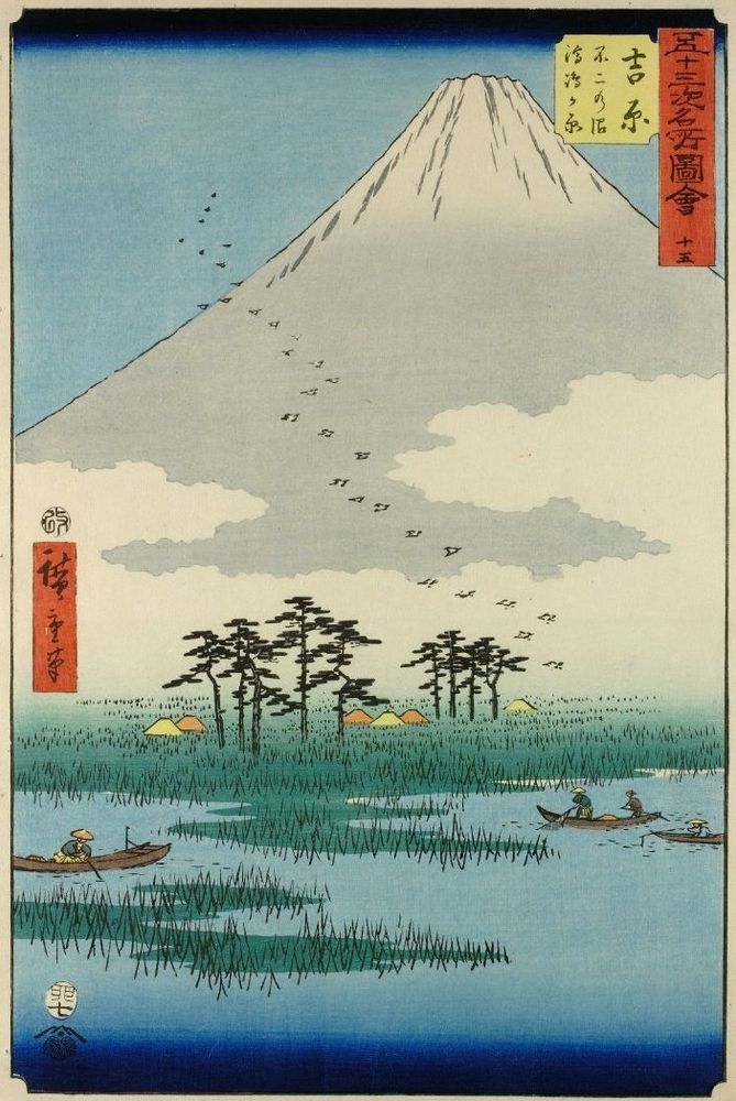 Mount Fuji is on the horizon. In the foreground are marshes with grass and trees and several small fishing boats. The sky is blue.