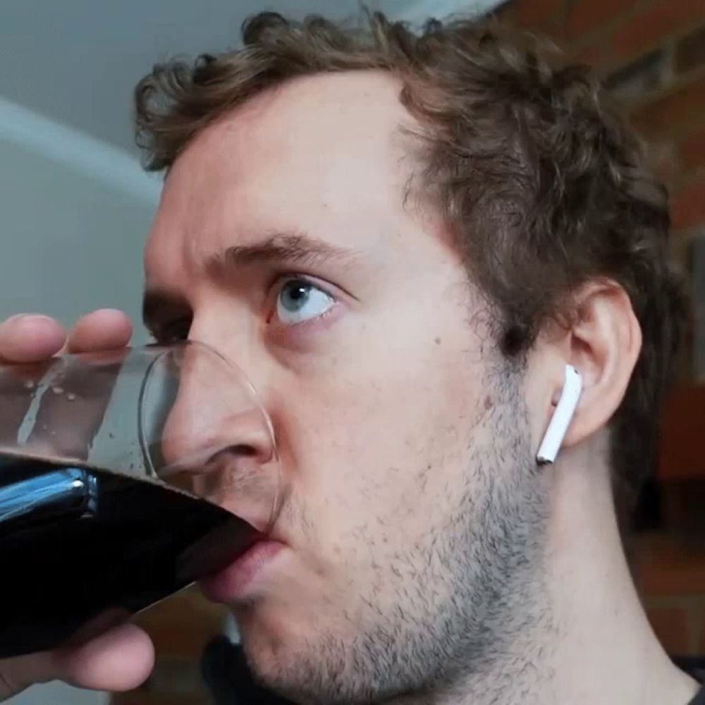 a man wearing ear buds is drinking a glass of beer