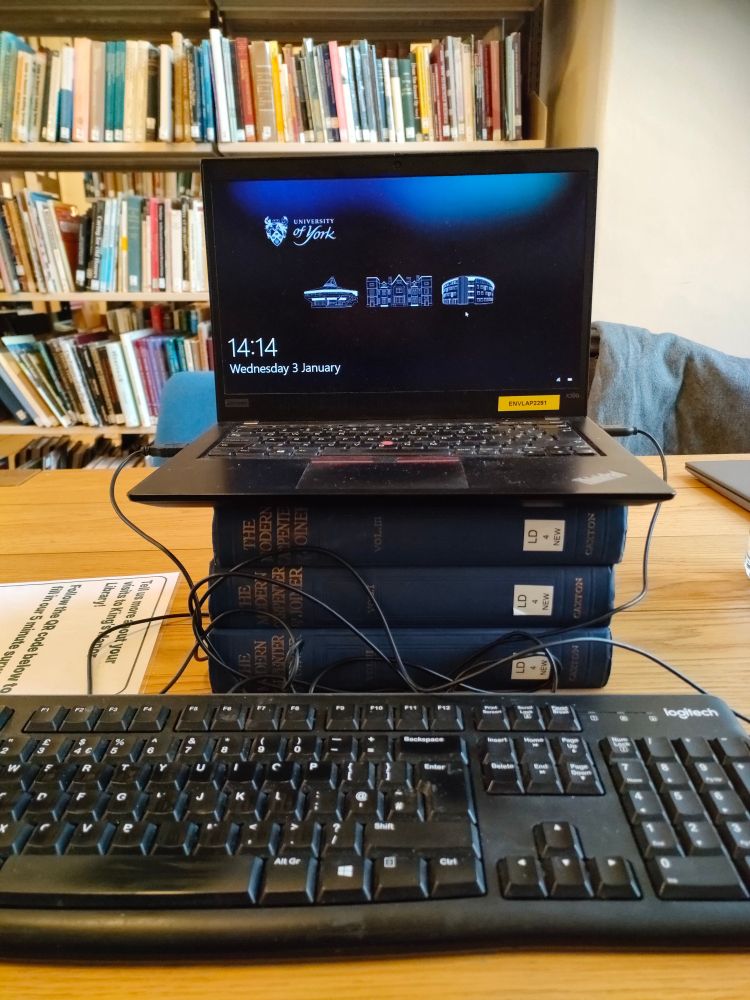 Laptop computer on top of a stack of 3 thick books