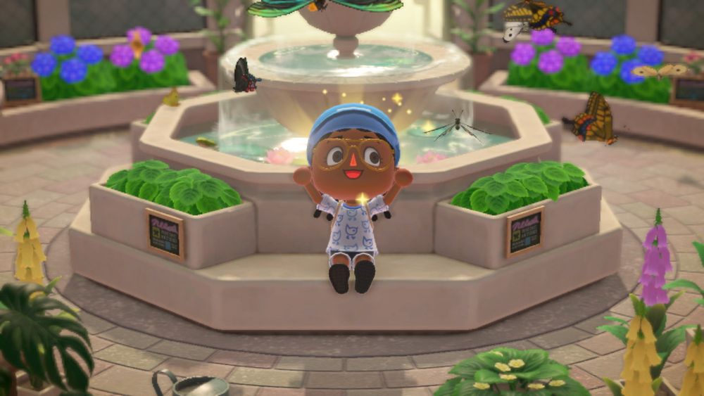 my animal crossing villager sitting in front of a fountain smiling. there are butterflies flying around