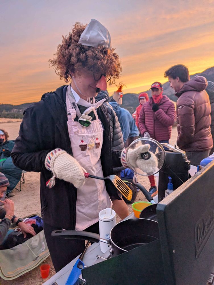 Early-morning preparation of snacks on a camp stove, wearing appropriate chef attire (apron, hat, wig, fake nose). Walker Ranch just outside of Boulder, CO
