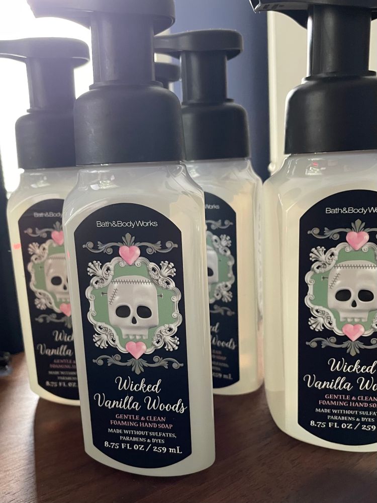 A photo of five bottles of Bath & Body Works “Wicked Vanilla Woods” foaming hand soap sitting on a walnut desk.