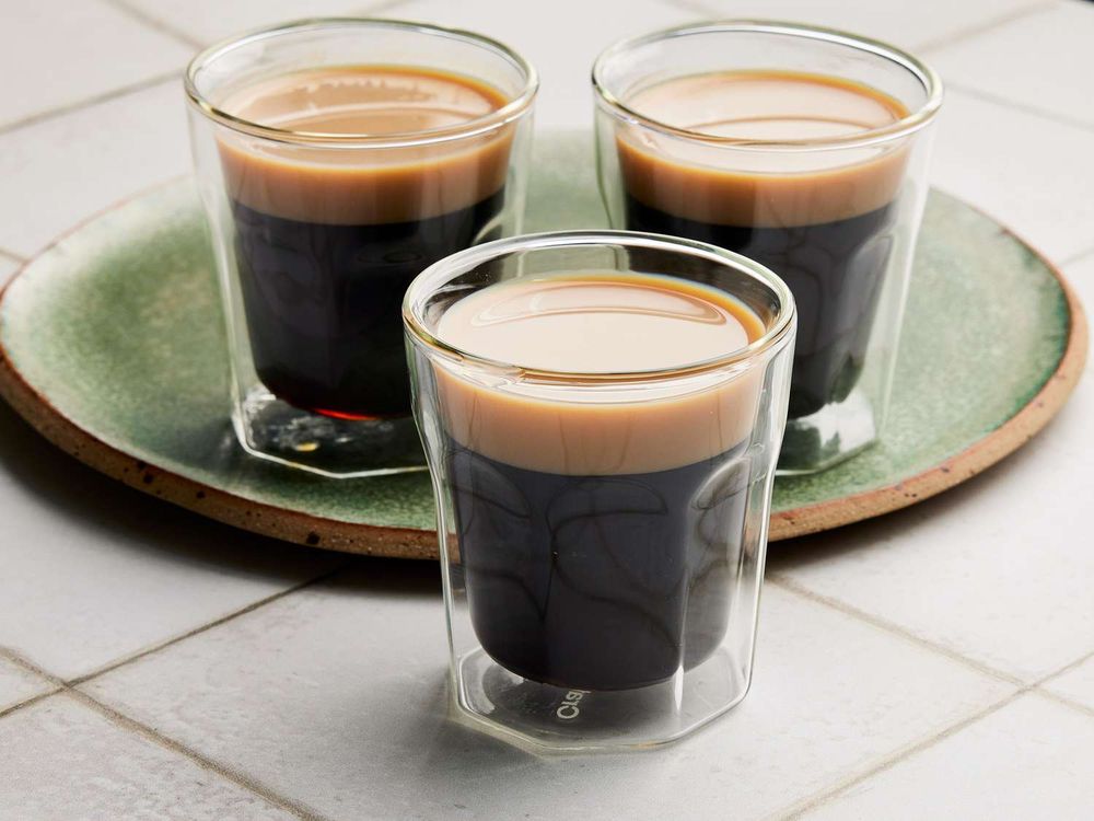 Three shot glasses of the shot 'Baby Guinness' which is a dark black liquor and a beige cream top akin to a pint of Guinness 